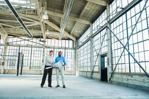 two men standing in warehouse with blueprints